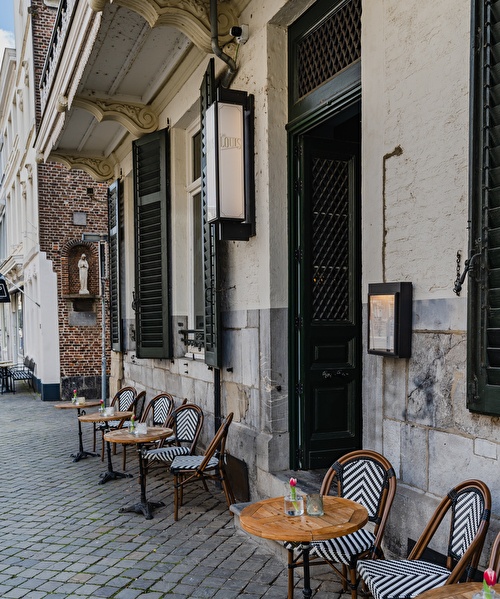 Exterior of Cafe Louis with tables and chairs next to the entrance.